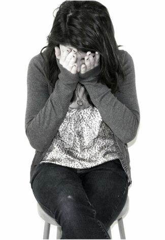 Woman sitting on stool with hands over her face, looking embarrassed