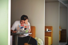 Picture of man holding forehead, working on something difficult on his laptop